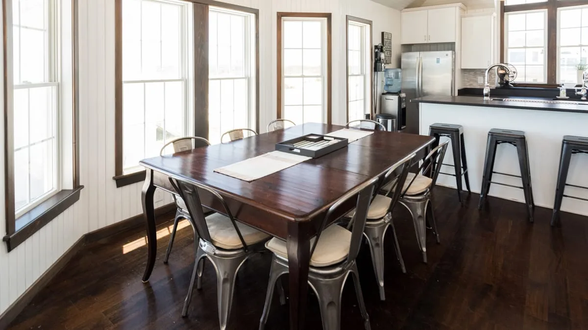 A dining area with a large wooden table beside a kitchen counter.