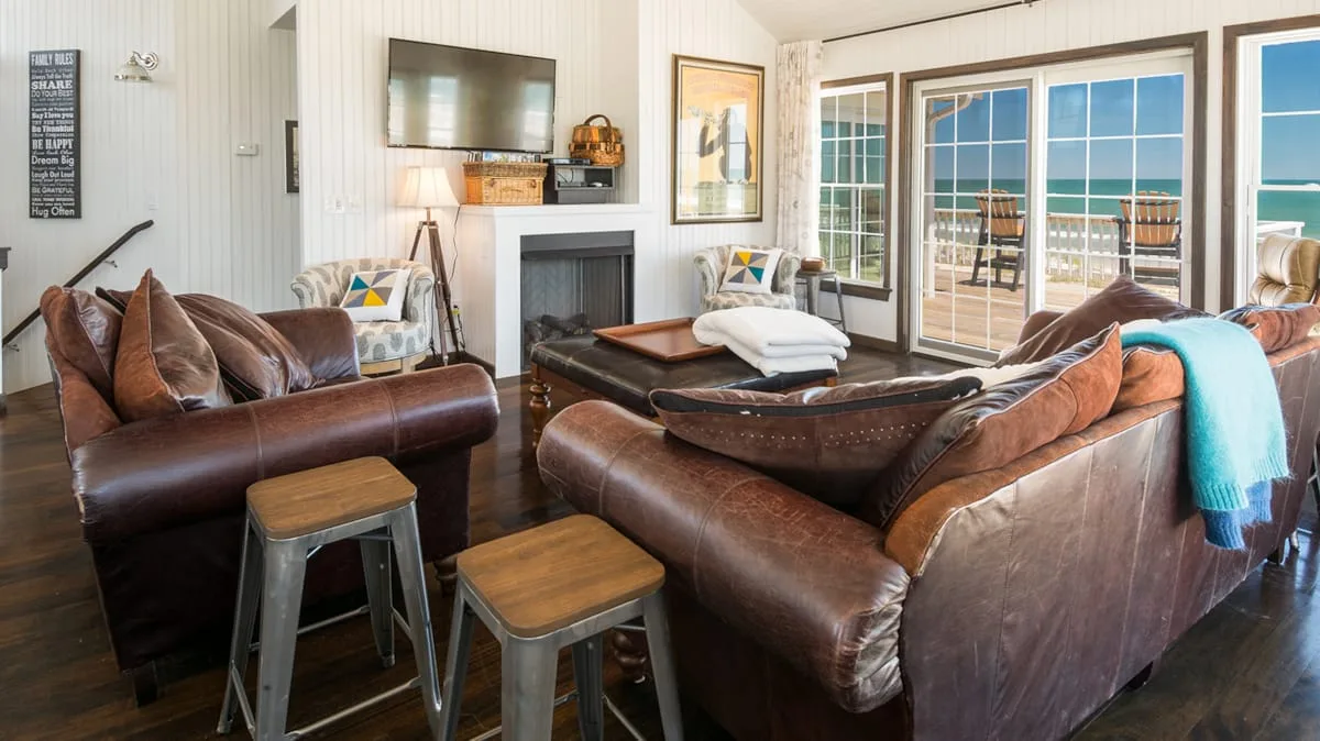 A living room with leather seating, a fireplace, and glass doors opening to a patio.