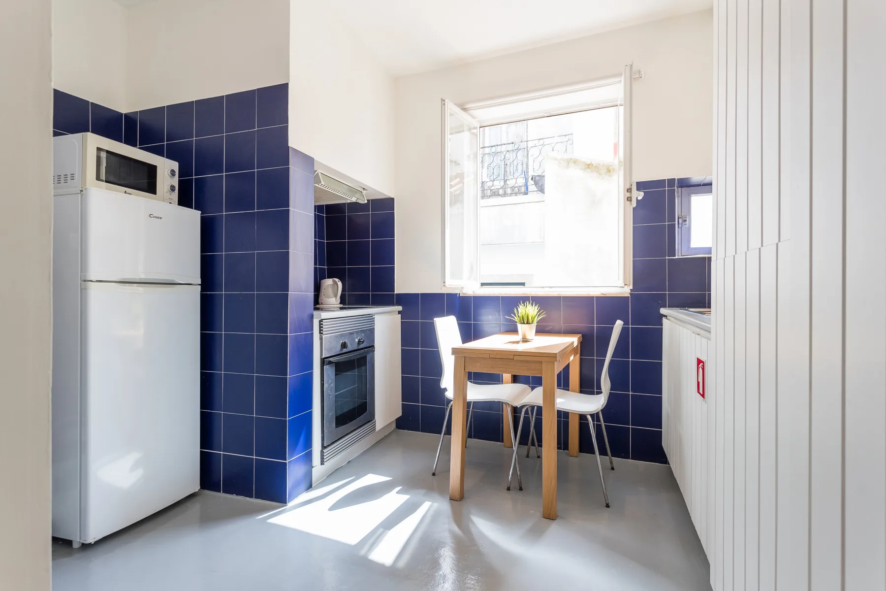 Una cocina luminosa con una pequeña mesa de comedor junto a una ventana soleada.