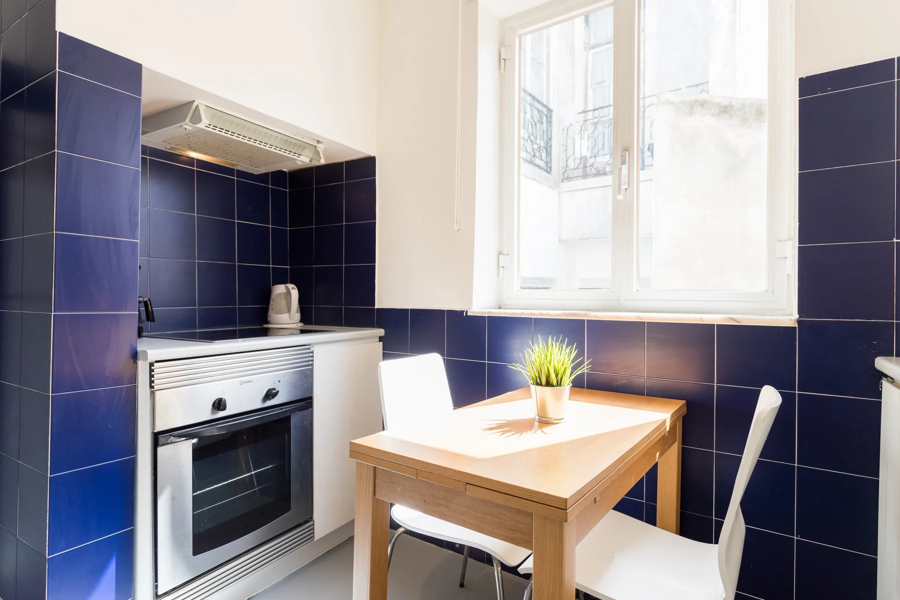 Una cocina pequeña con estufa, mesa de madera y ventana.