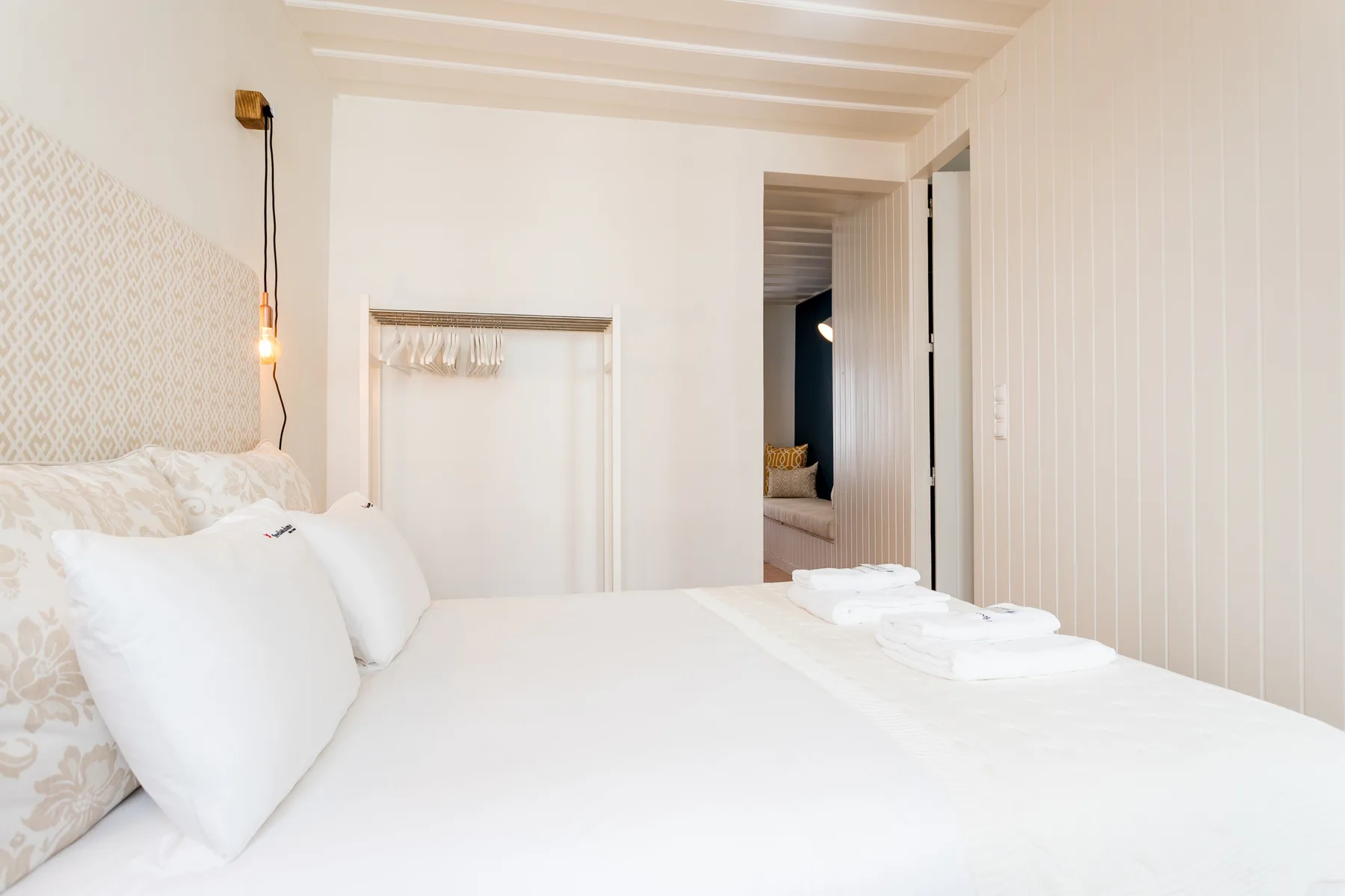 Un dormitorio luminoso con una cama bien hecha y una puerta abierta.