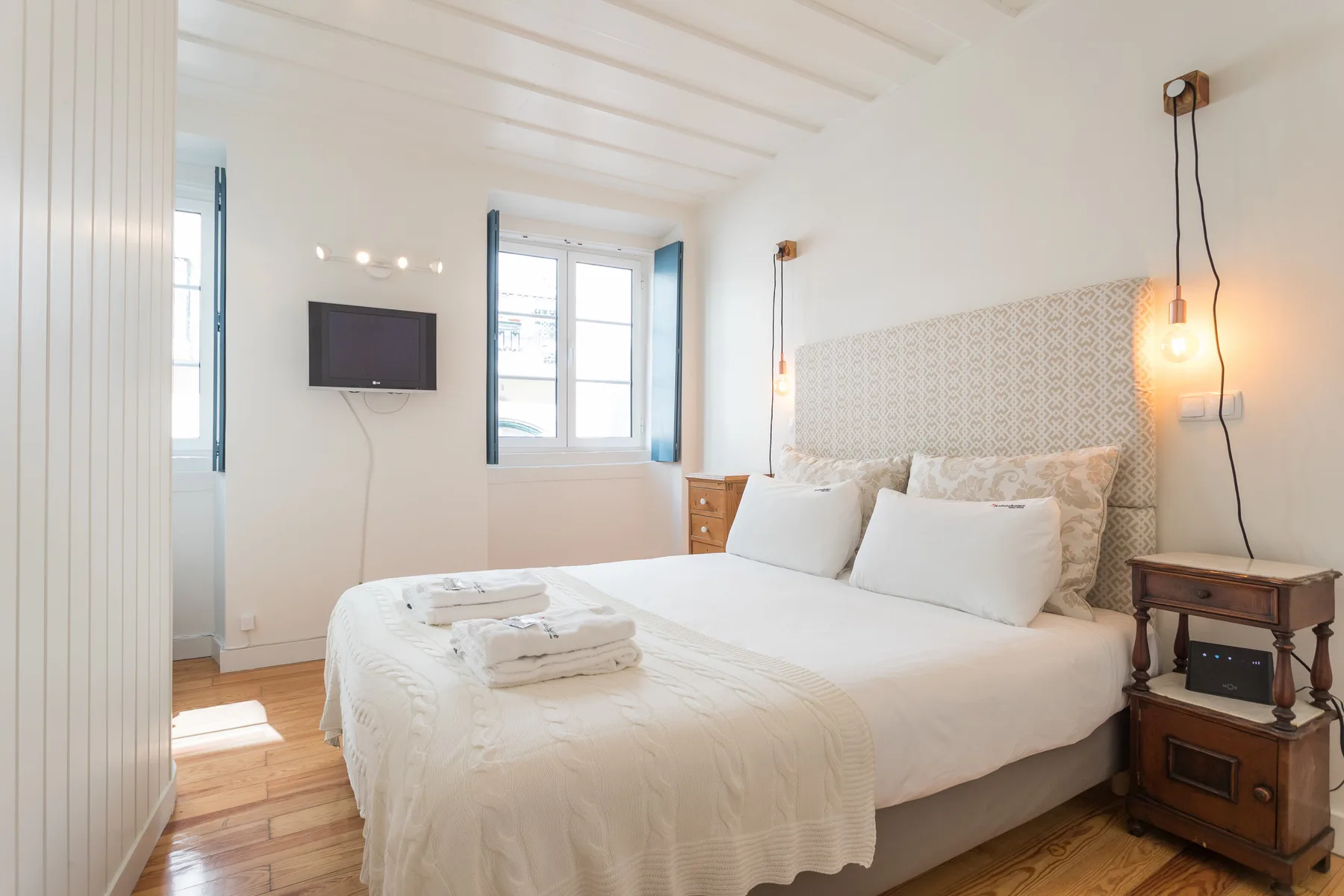Un dormitorio luminoso con una cama bien tendida y una ventana.