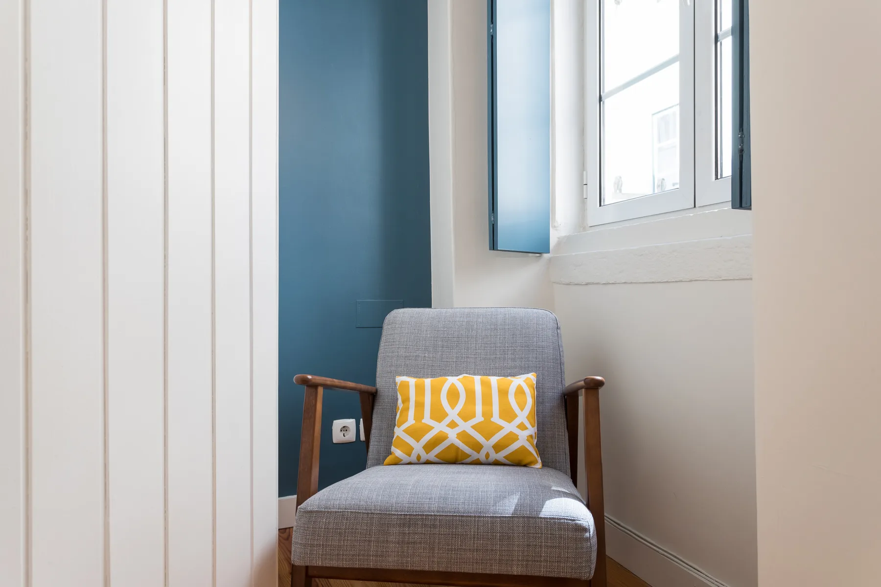 A bright room with a gray armchair beside a window.