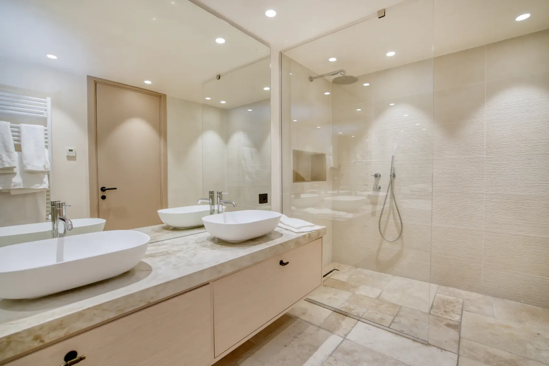Un baño luminoso con un tocador largo y una ducha de cristal.