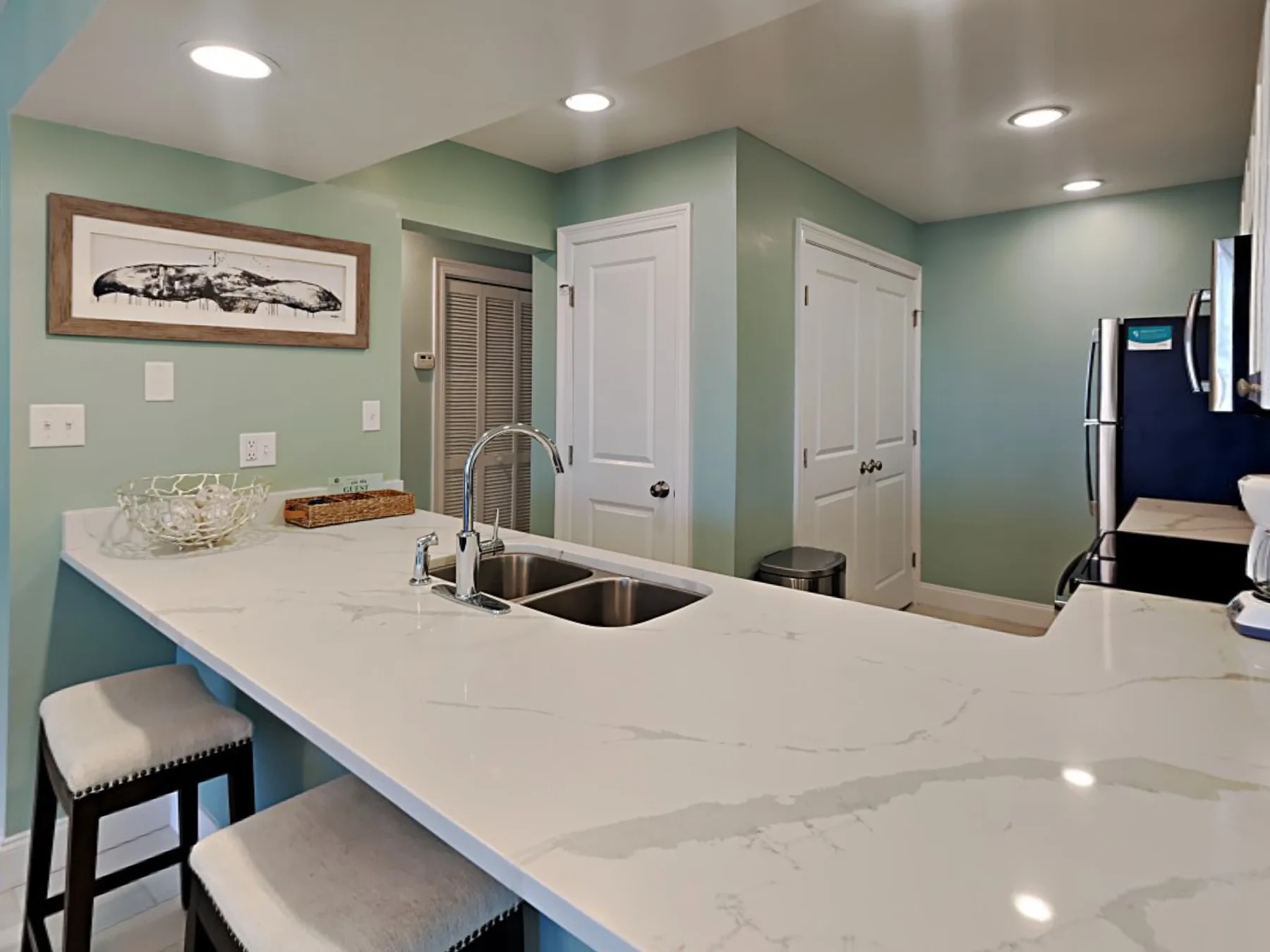 A kitchen with a large counter, sink, and refrigerator.
