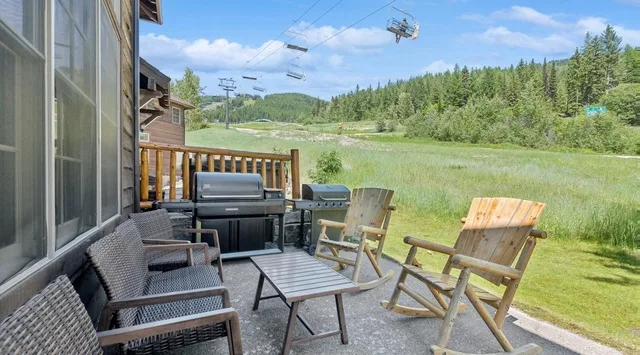 Un patio al aire libre con asientos y una parrilla da a un paisaje de hierba.