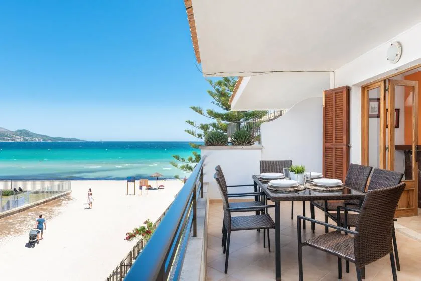 Una zona de comedor en el balcón da a una playa de arena y un mar turquesa.