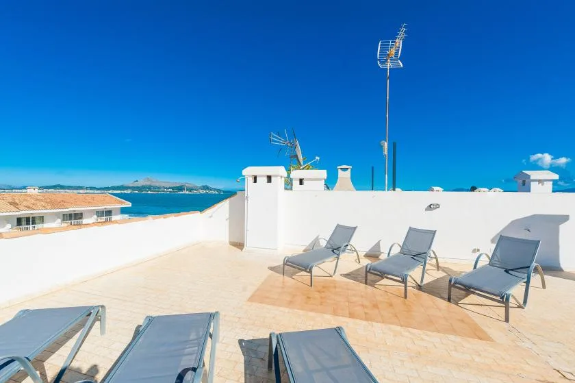Una soleada terraza en la azotea con asientos y vistas al mar.