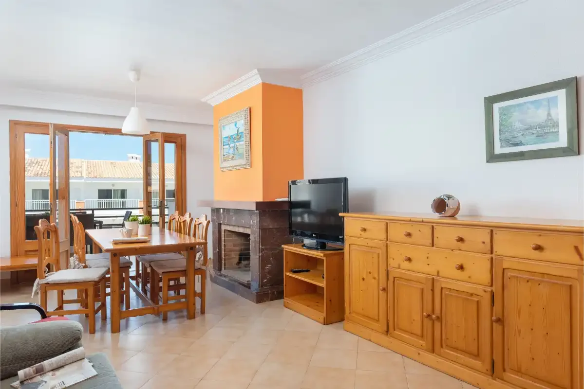 Una zona de estar y comedor con muebles de madera, un televisor y una chimenea.