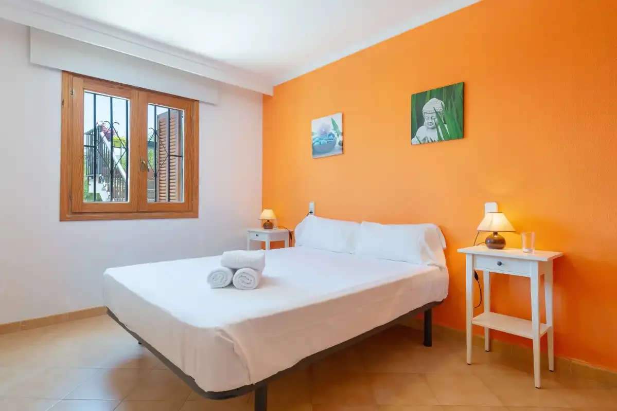 Un dormitorio con una cama junto a una pared naranja.