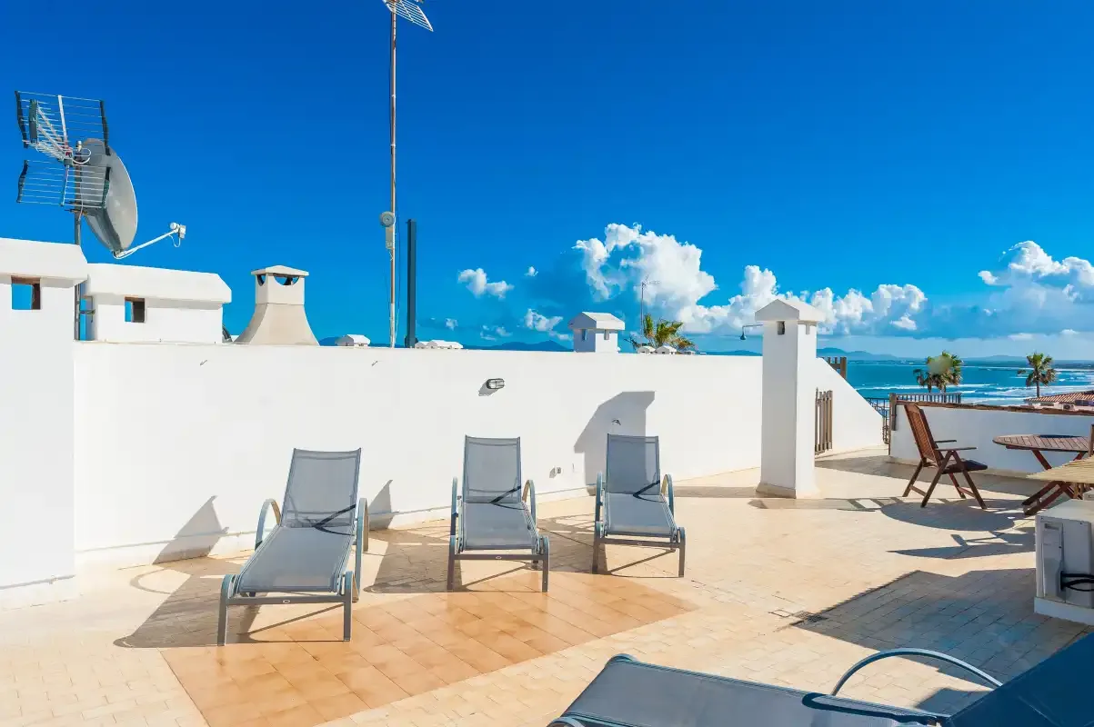 Una terraza en la azotea con asientos reclinables y vistas al mar.