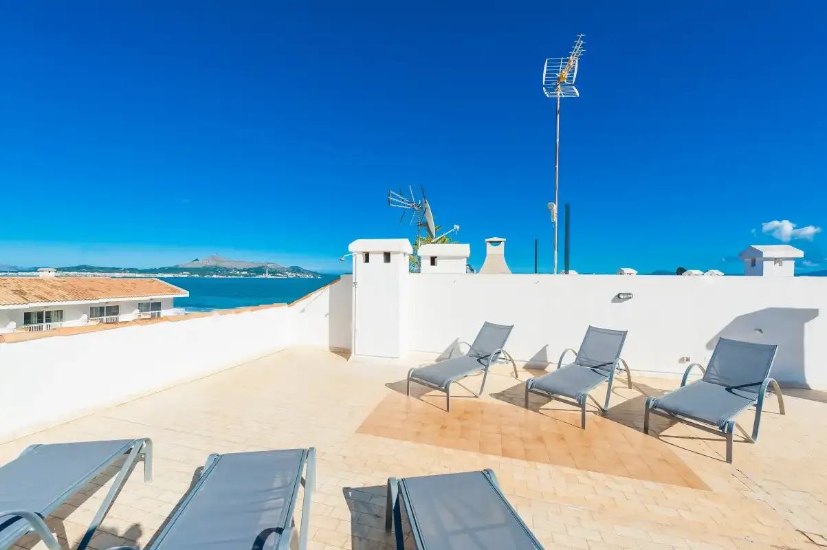 Una terraza soleada en la azotea con asientos y vistas al mar.