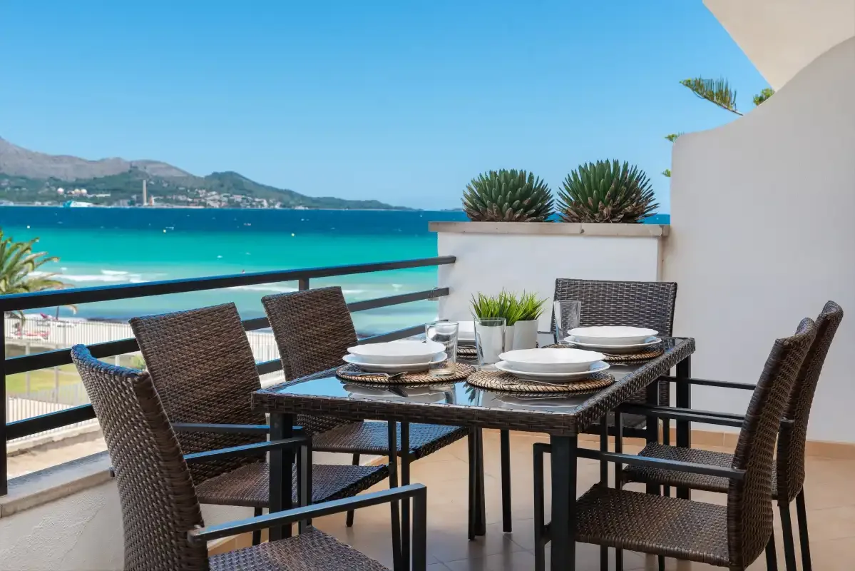 Una zona de comedor al aire libre da al mar turquesa y a la costa distante.