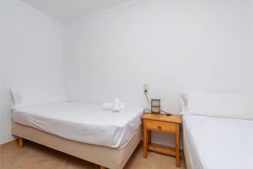 Un dormitorio con dos camas y una pequeña mesa de noche de madera.