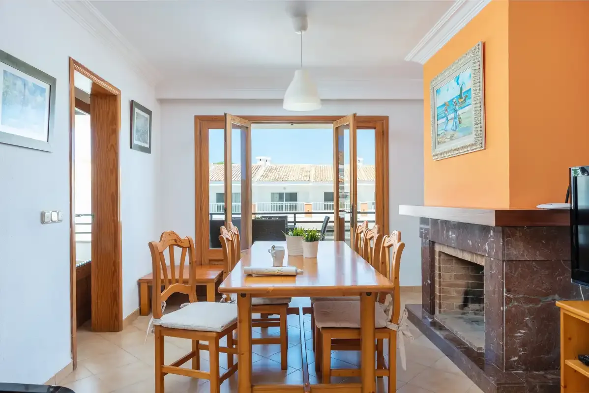Un comedor con una mesa de madera y sillas junto a una chimenea.