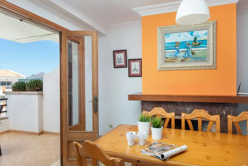Comedor con una mesa de madera, sillas y cuadros coloridos en la pared.
