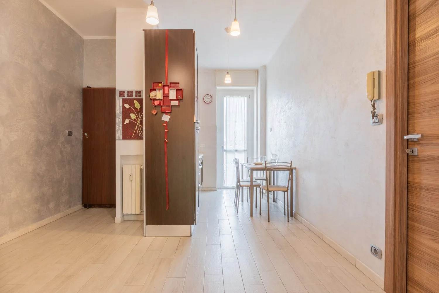 Un comedor con una mesa y sillas junto a un refrigerador alto.