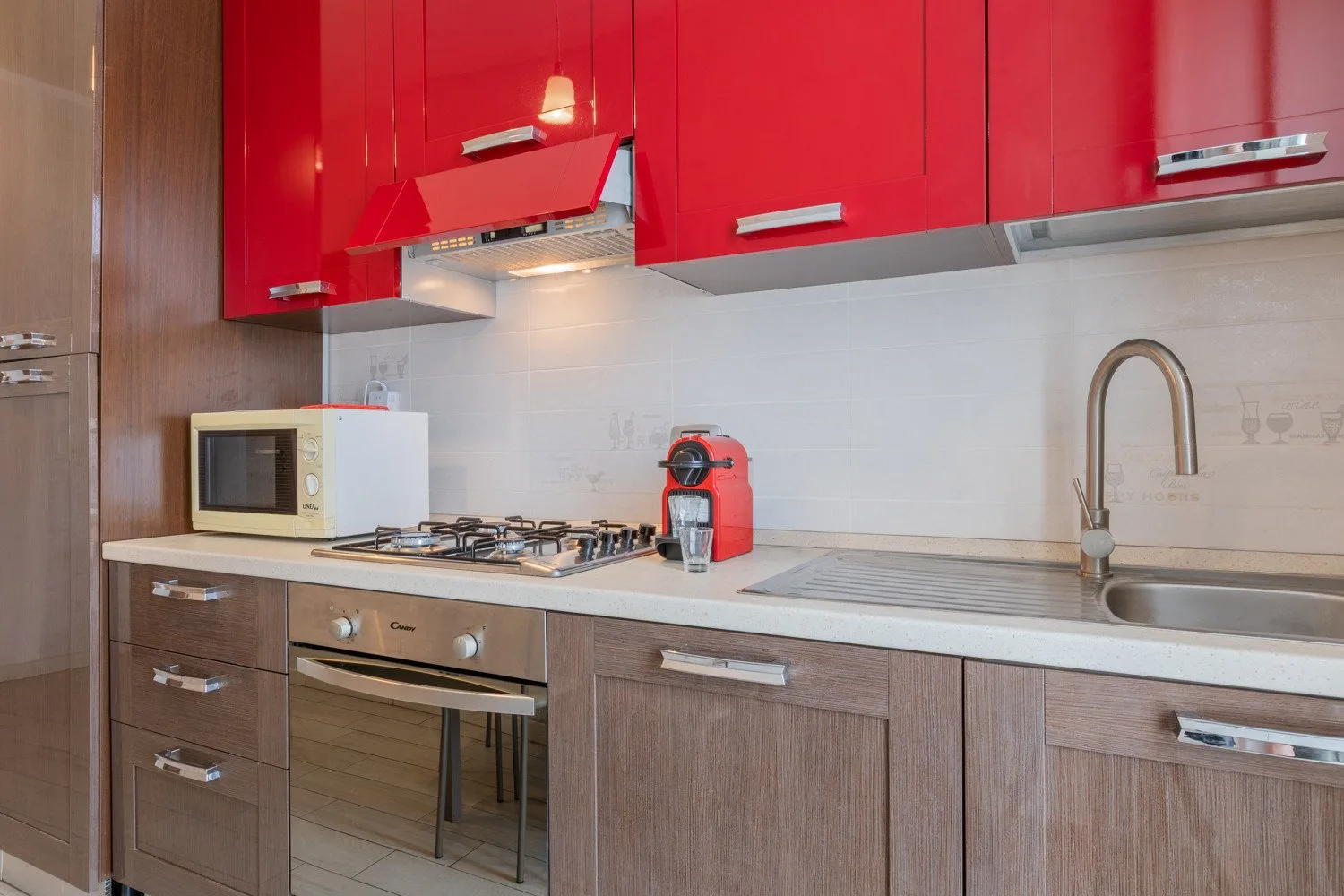 Una cocina con gabinetes rojos, una estufa y un fregadero junto a la encimera.