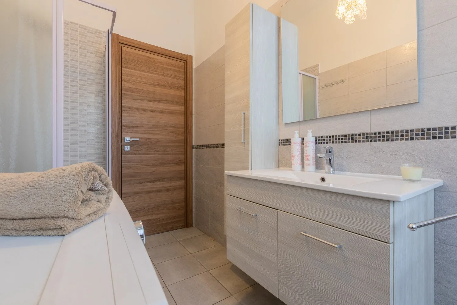 Un baño con un amplio tocador, espejo y toallas dobladas.