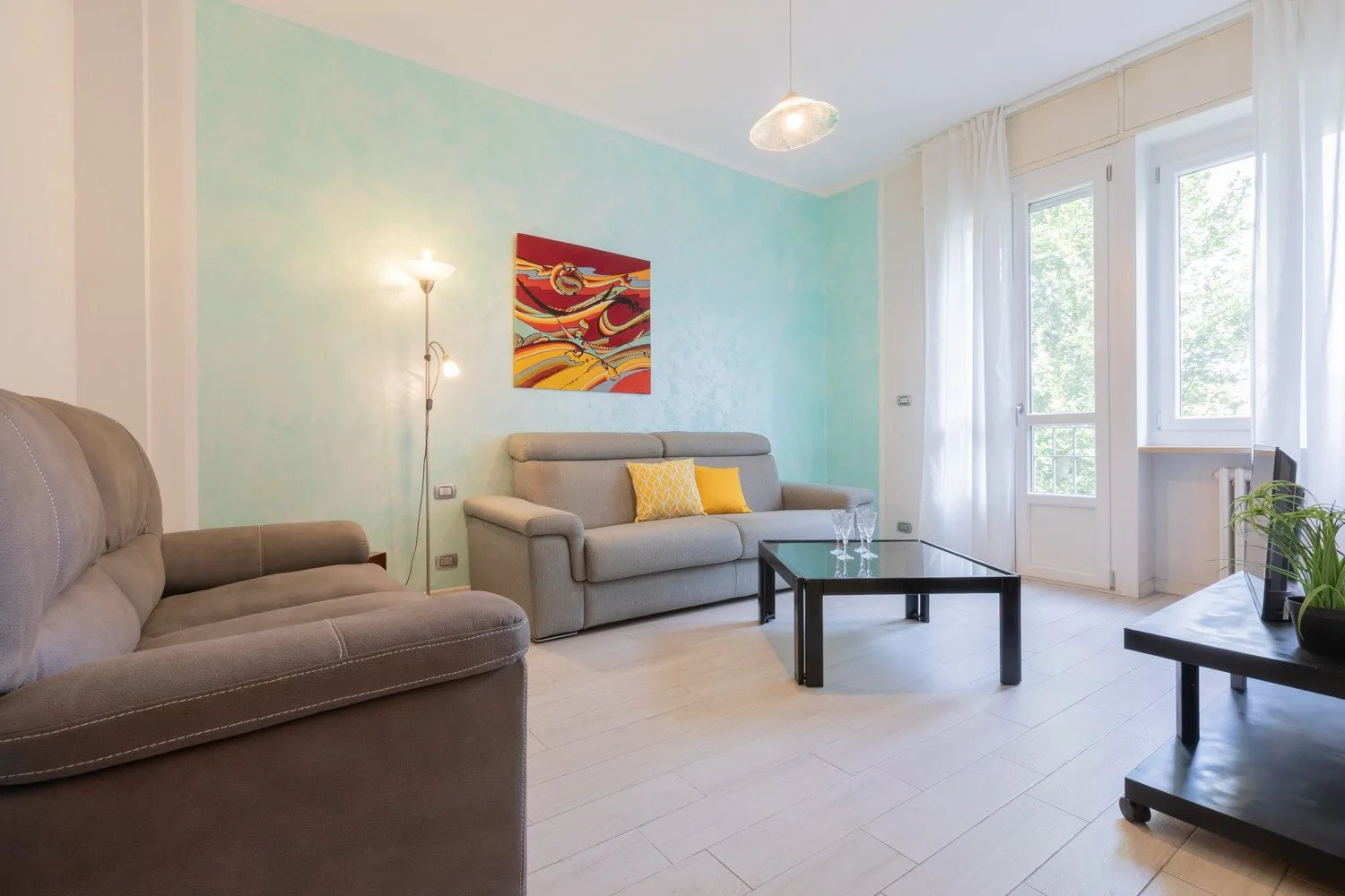 Una sala luminosa con asientos, una mesa de centro negra y arte colorido en la pared.