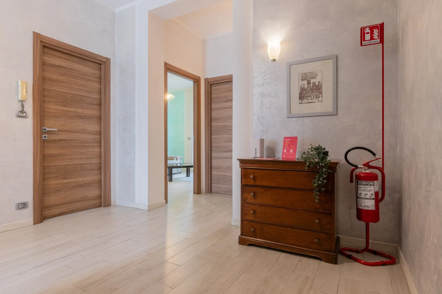 Un pasillo con puertas de madera y una cómoda bajo un cuadro enmarcado.