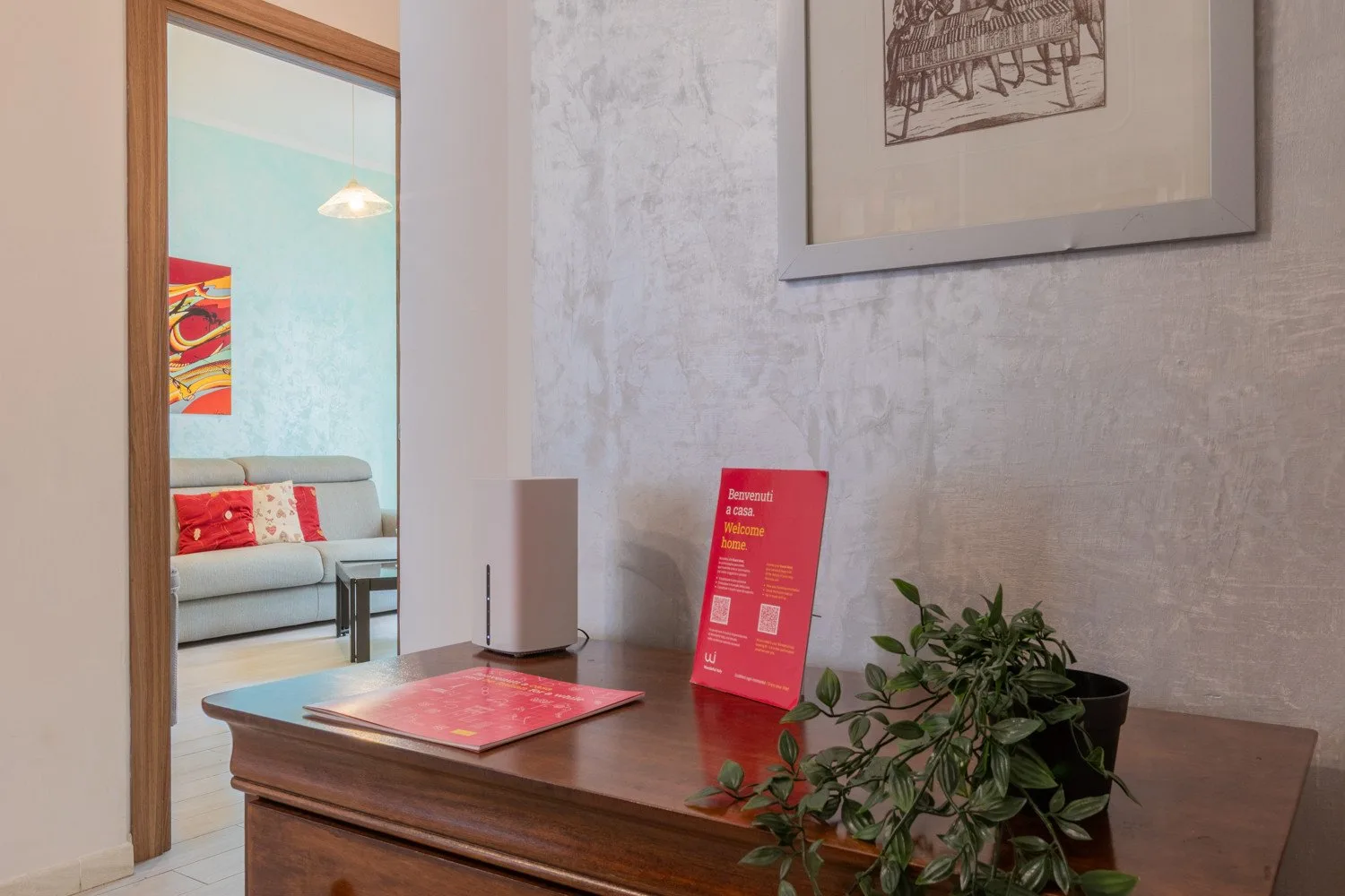 Un escritorio de madera tiene un folleto rojo y una planta junto a una puerta.
