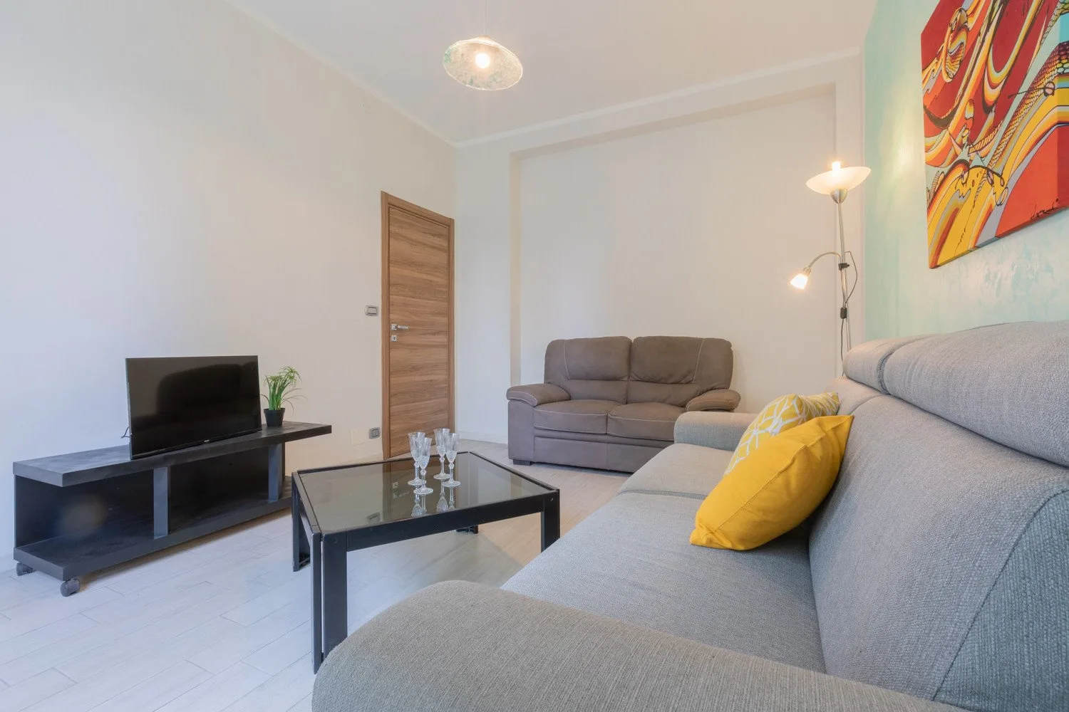 Sala de estar con asientos, un televisor y una mesa de centro de vidrio.