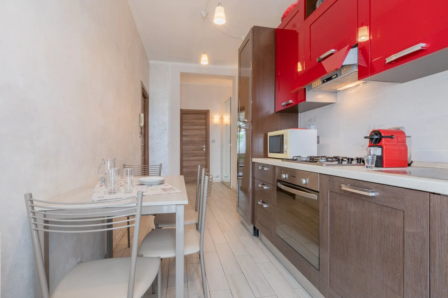 Una cocina estrecha con una mesa de comedor junto a una fila de gabinetes y electrodomésticos.