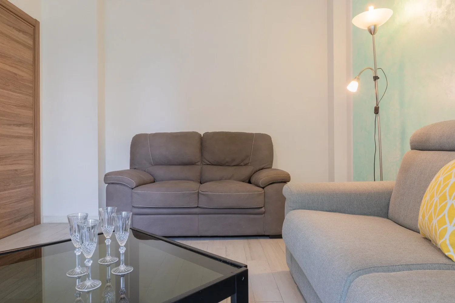 Una sala de estar con asientos grises y una mesa de centro de vidrio.