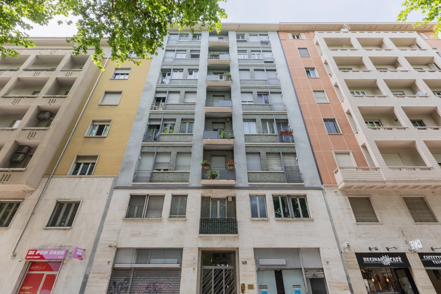 Vista desde la calle hacia un edificio de apartamentos de varios pisos con balcones.