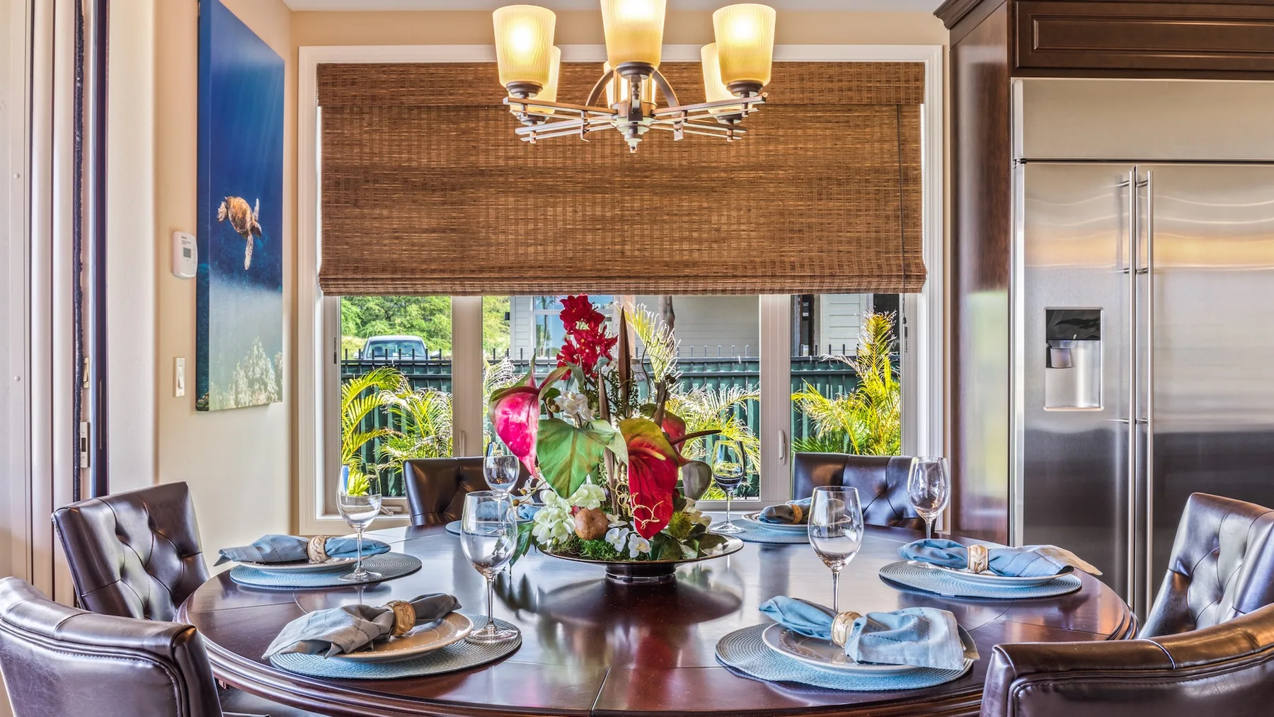 Un comedor con una mesa puesta y una gran ventana con vegetación a la vista.