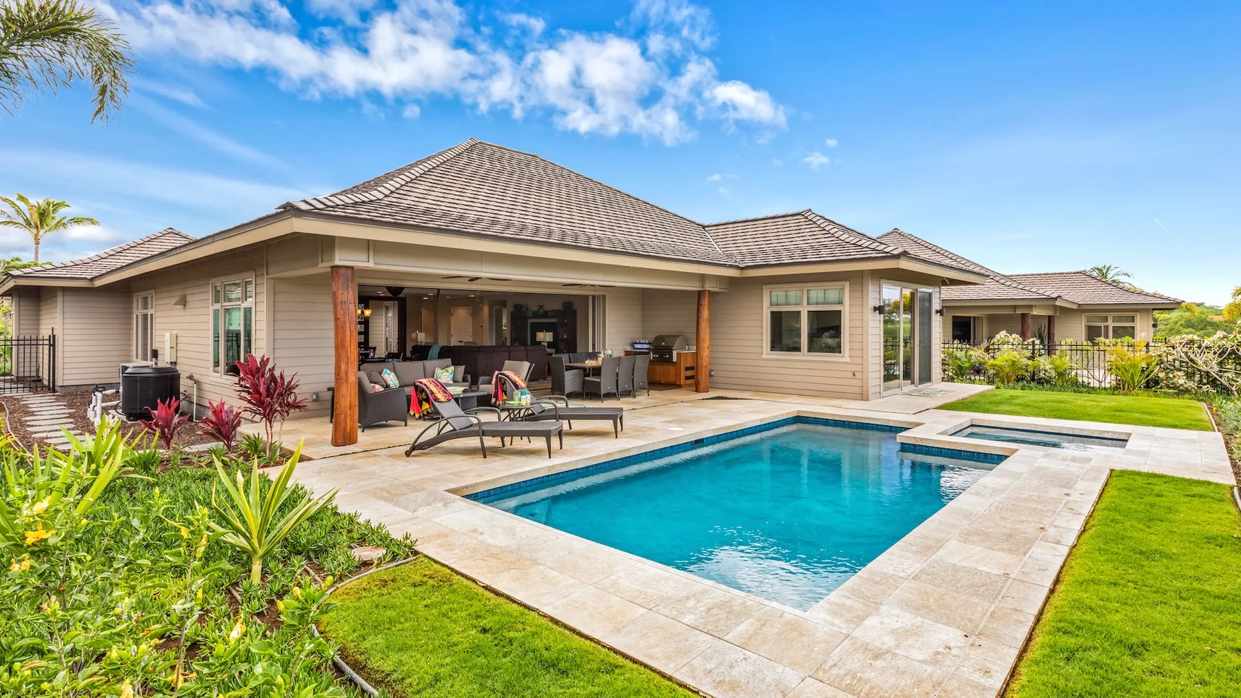 Una casa se abre a un patio con piscina y césped ajardinado.