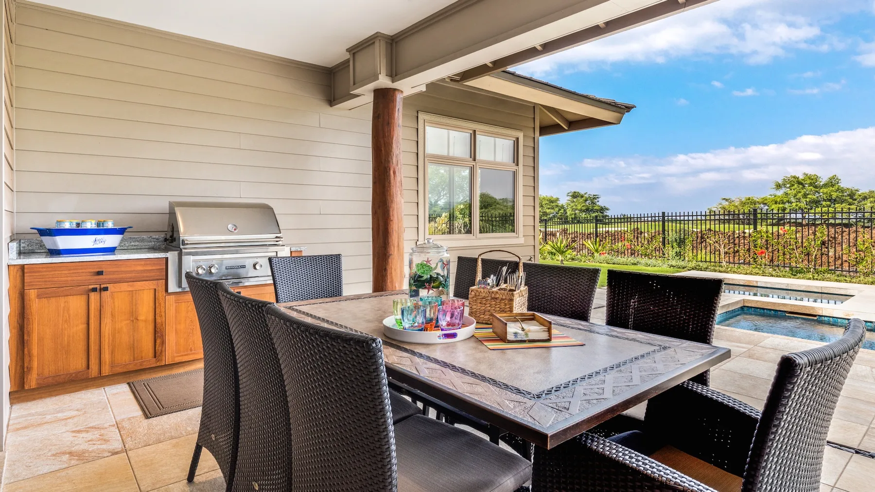 Comedor al aire libre con una mesa y asientos junto a una piscina.