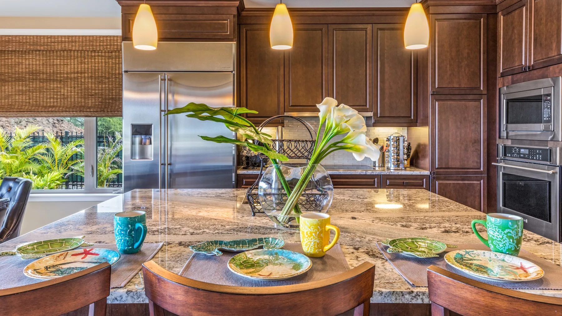 Una isla de cocina con la mesa puesta y un jarrón de flores.