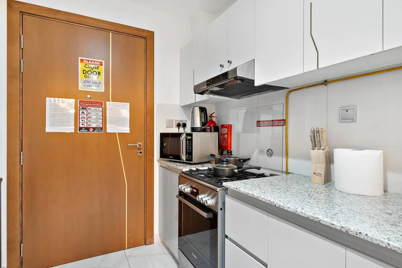 Una cocina compacta con gabinetes blancos, una estufa y un microondas.