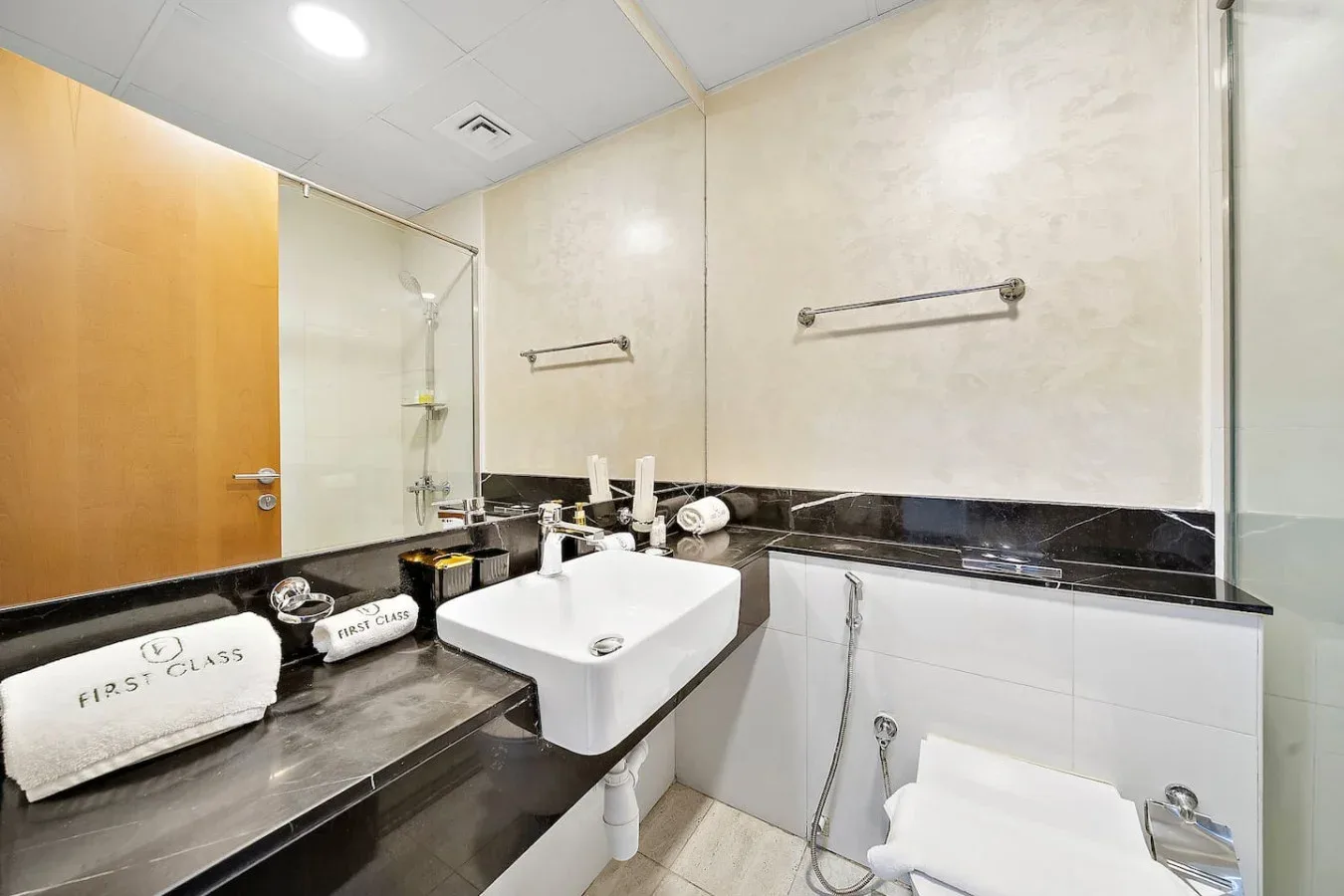 Un baño luminoso con lavabo blanco, inodoro y encimera oscura.