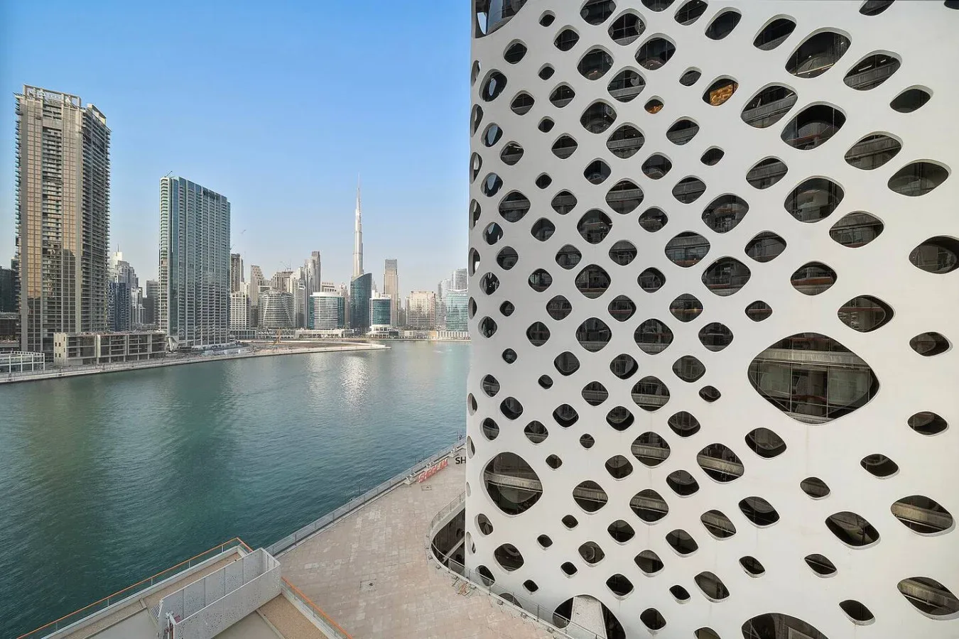 Un horizonte urbano junto al agua y un edificio blanco con aberturas ovaladas.