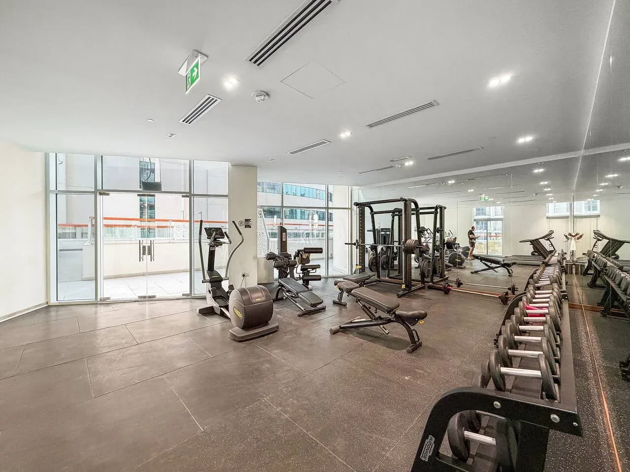 Un gimnasio con máquinas de pesas, bicicletas estáticas y mancuernas junto a la pared.