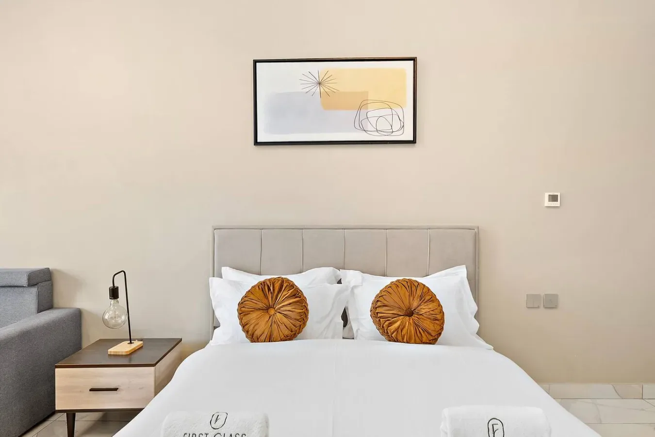 Un dormitorio con una cama tendida y dos cojines decorativos redondos.