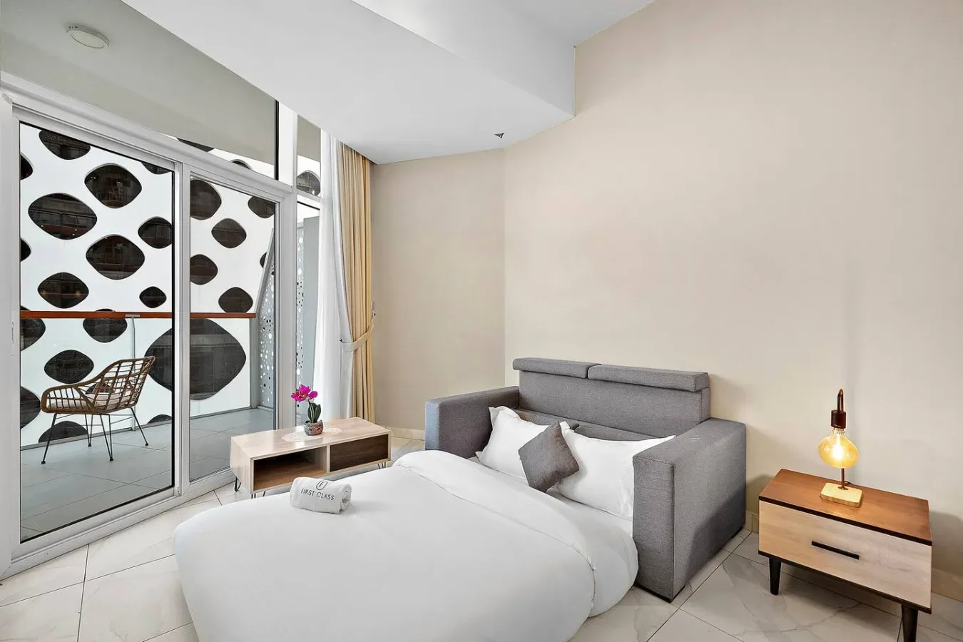 Un dormitorio con cama, asientos grises y ventanales.