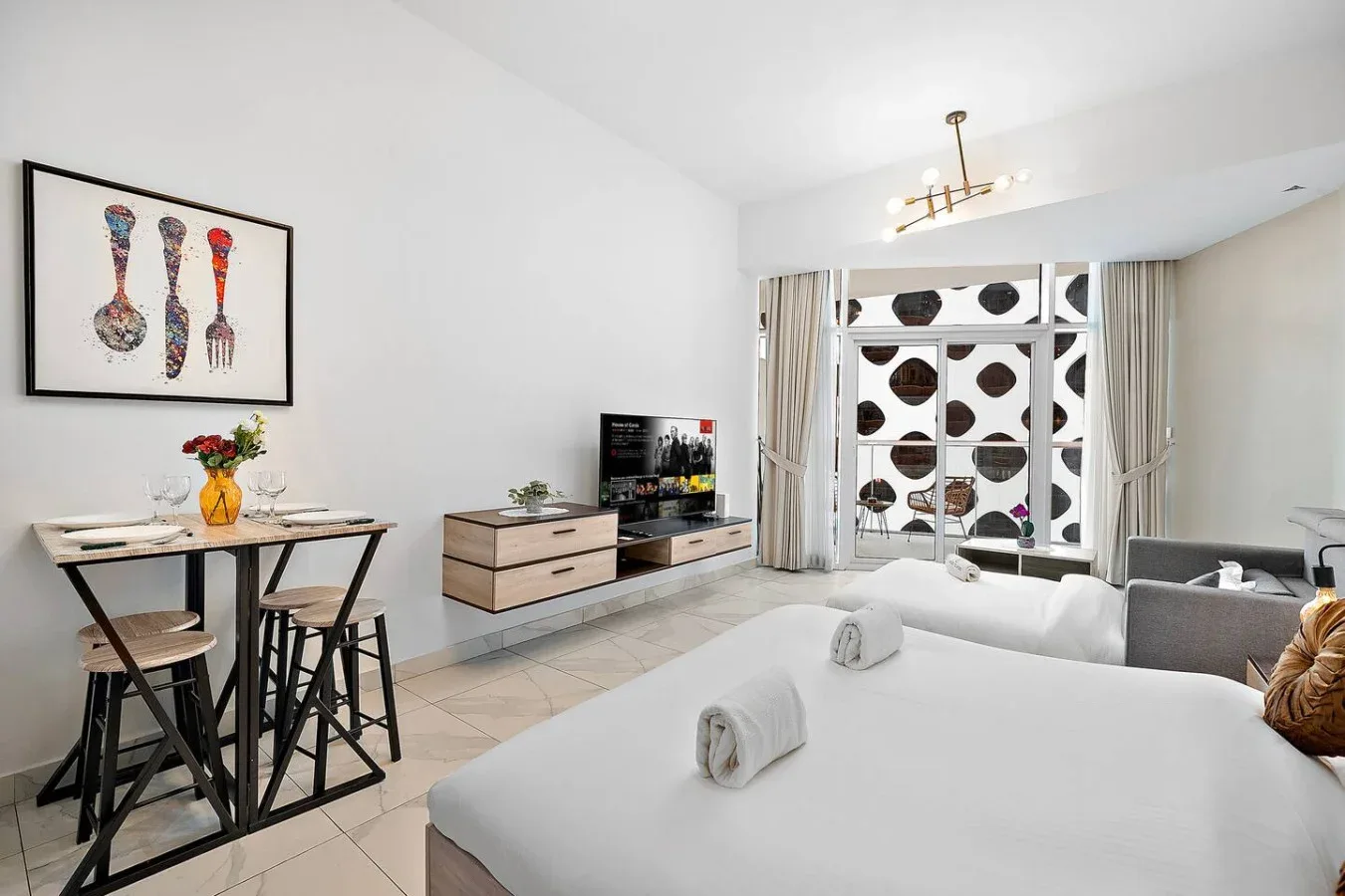 Un dormitorio luminoso con dos camas, un televisor y una pequeña mesa de comedor.