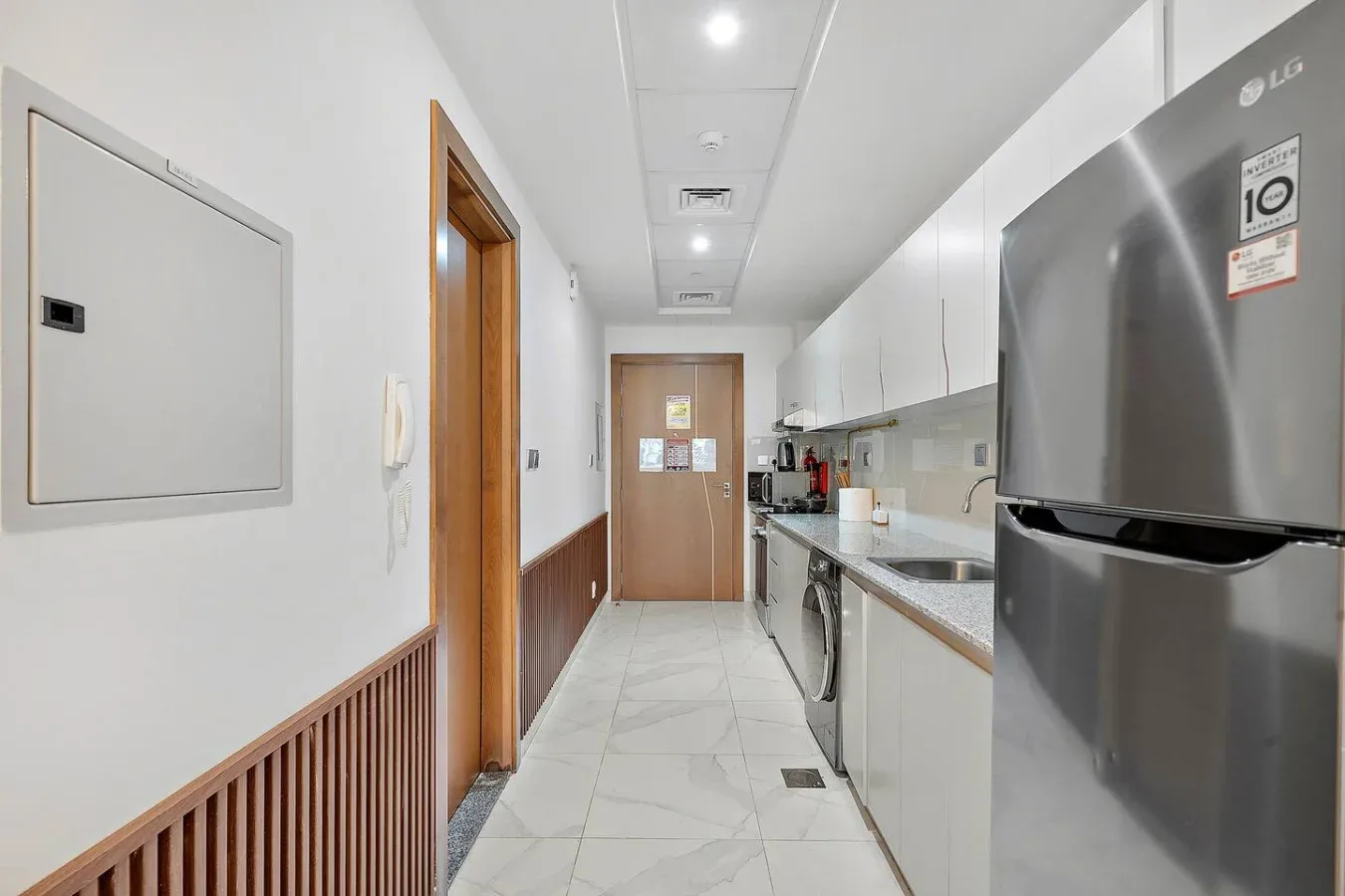 Un pasillo estrecho de cocina con encimeras y un refrigerador.
