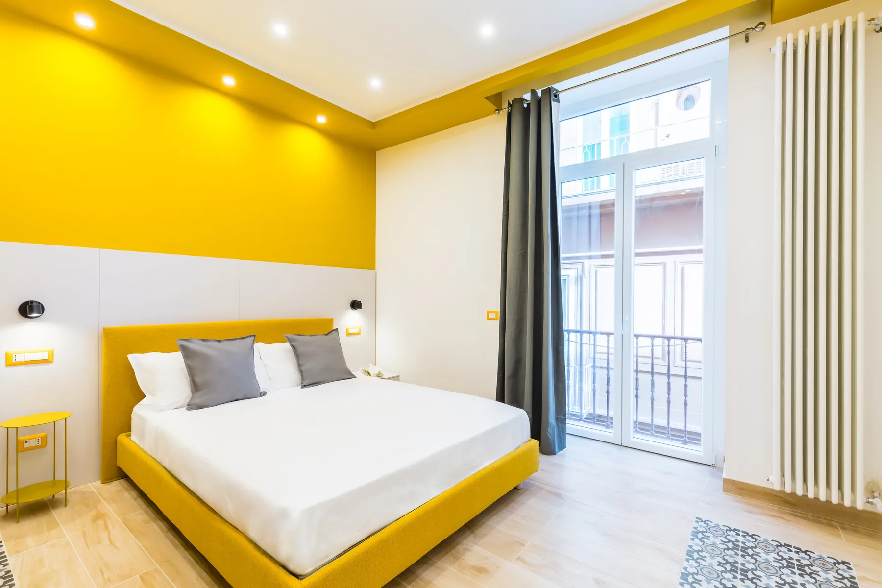 A bedroom with a yellow bed and a large window.