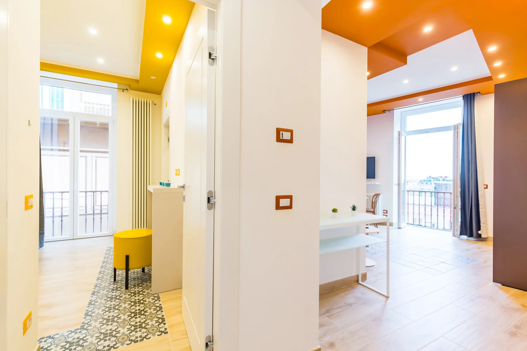 A bright interior hallway opens onto a room with a large window and balcony doors.