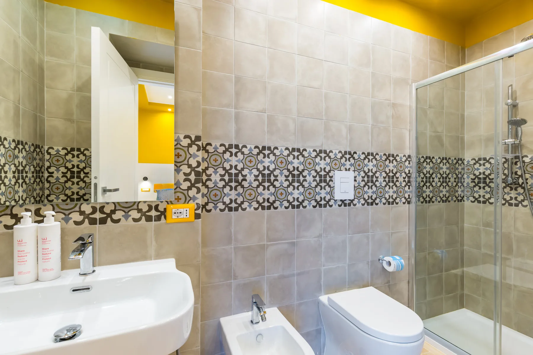 A tiled bathroom with a sink, toilet, and glass-enclosed shower.