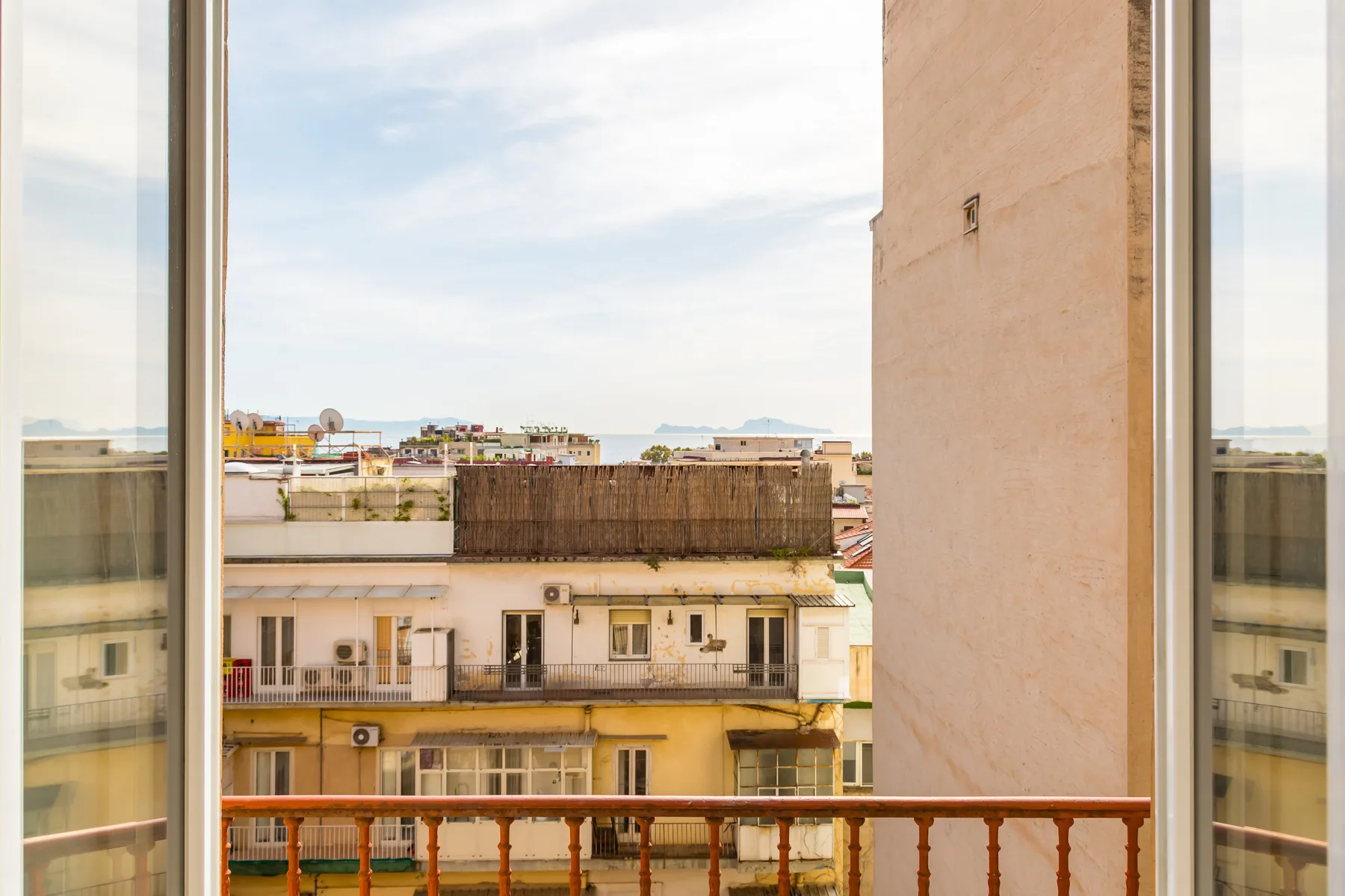 A balcony overlooks nearby buildings and a distant stretch of water.