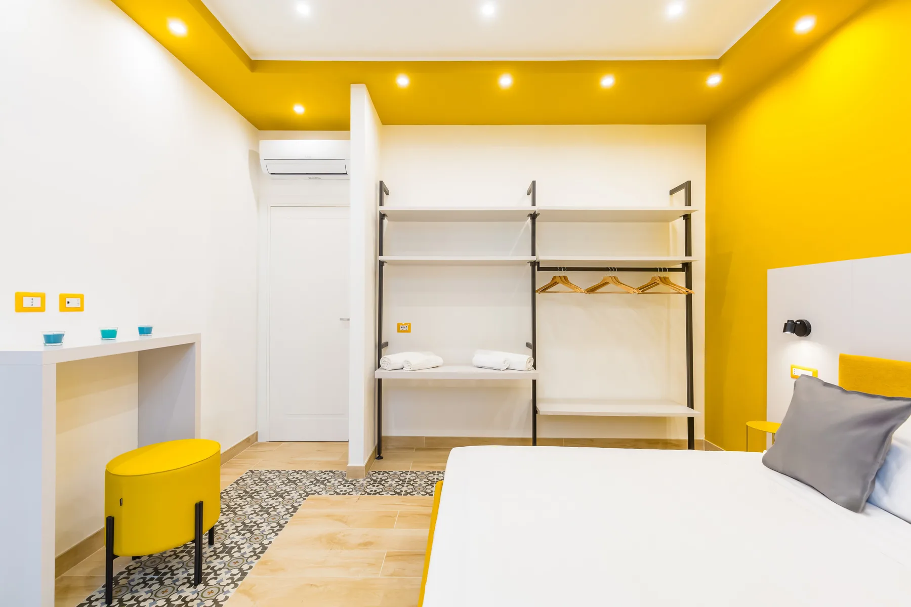 Bedroom with a white bed, open shelving, and a bright yellow ceiling.
