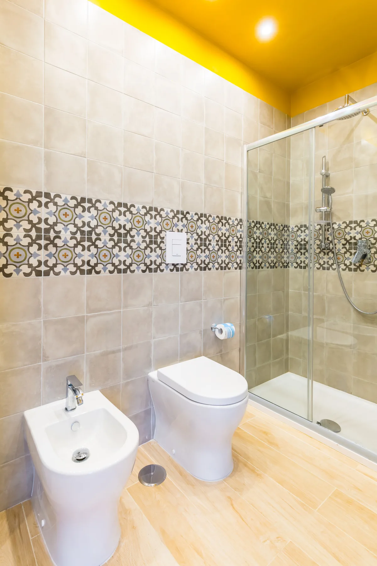 A tiled bathroom with a toilet, bidet, and glass shower.