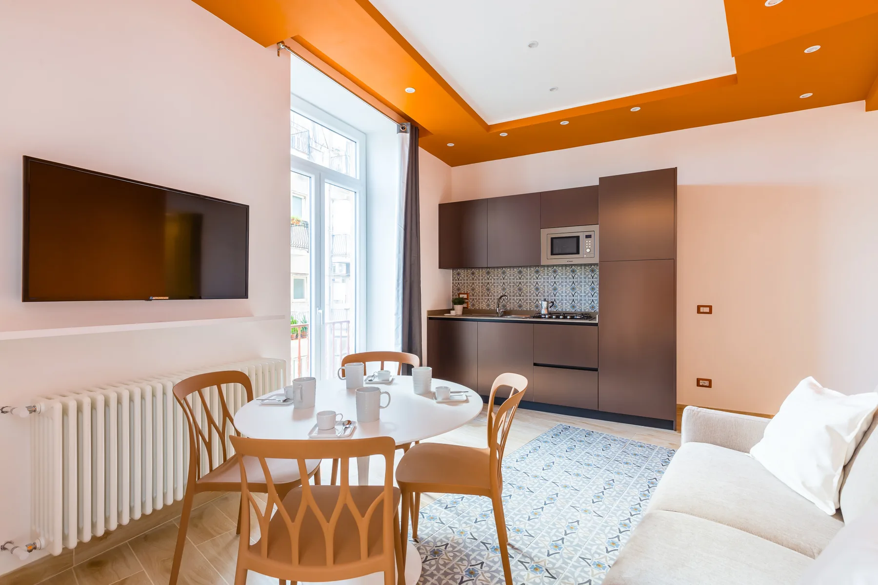 A bright open-plan living and dining area with a compact kitchen and large windows.