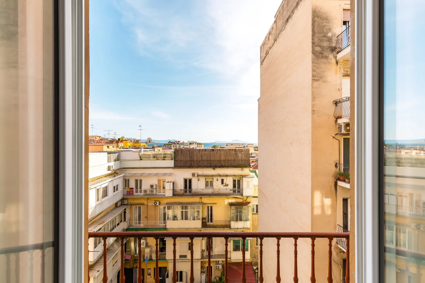 A city view from a window, with nearby apartment buildings and balconies.